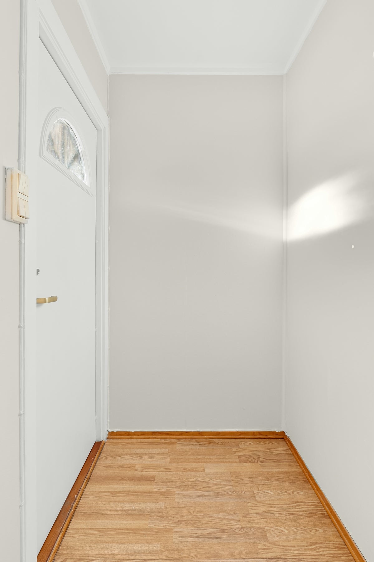 An empty room with a door and a hard wood floor