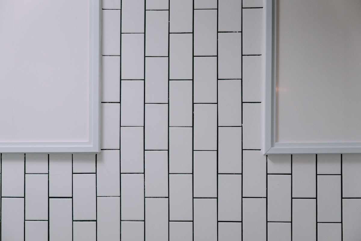 A bathroom with a white tiled wall and two mirrors