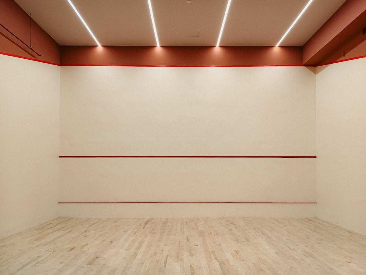 Empty squash court with red markings and lighting.