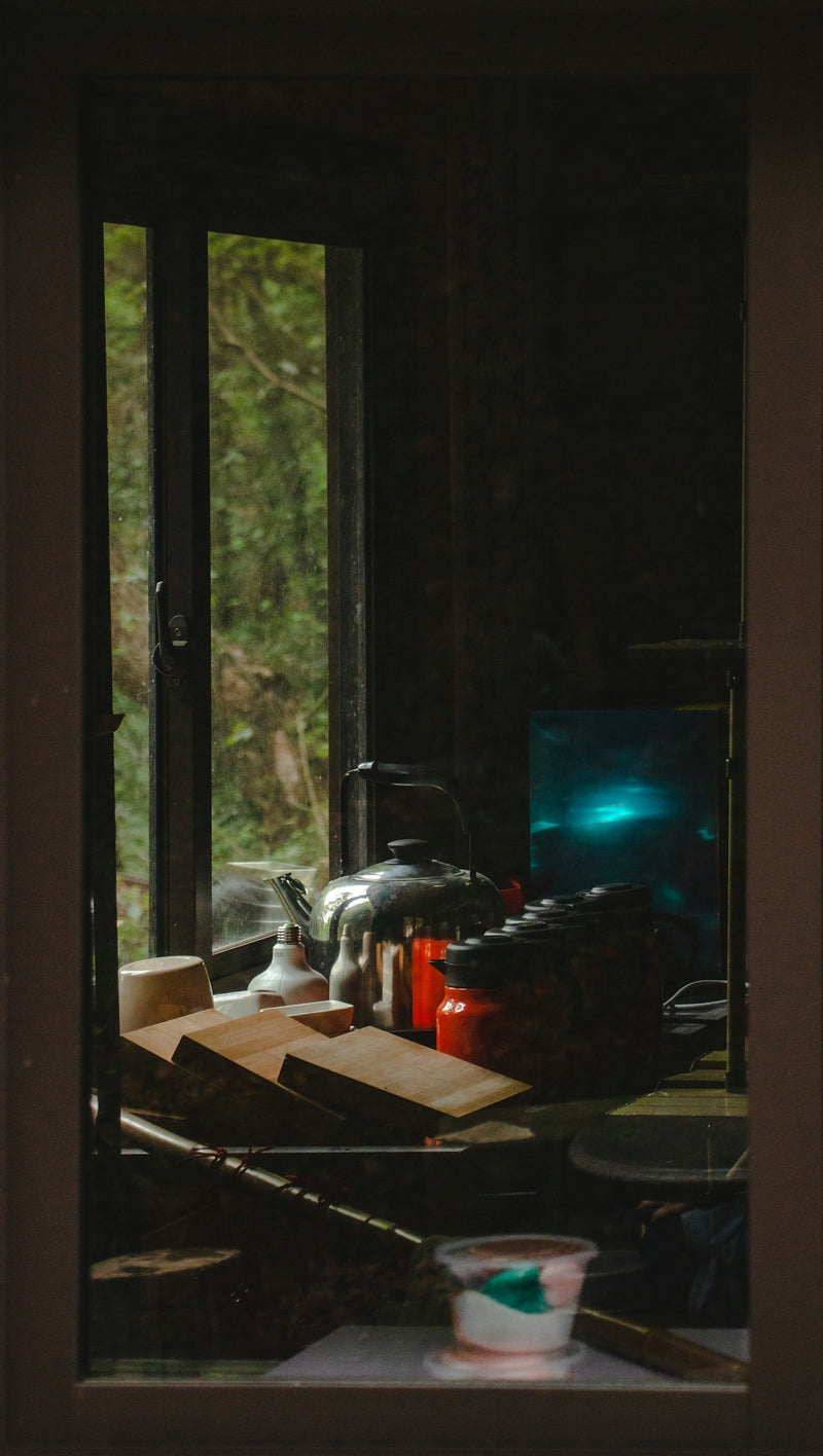 Pots and boards on a windowsill with an outdoor view.