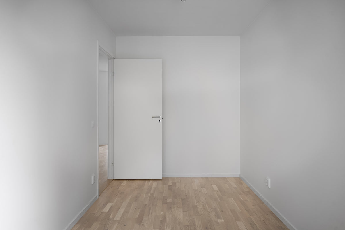 An empty room with a door and a ceiling fan