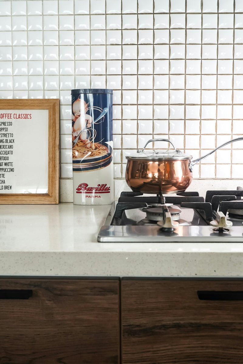 A copper pot sits on the stovetop in a kitchen.