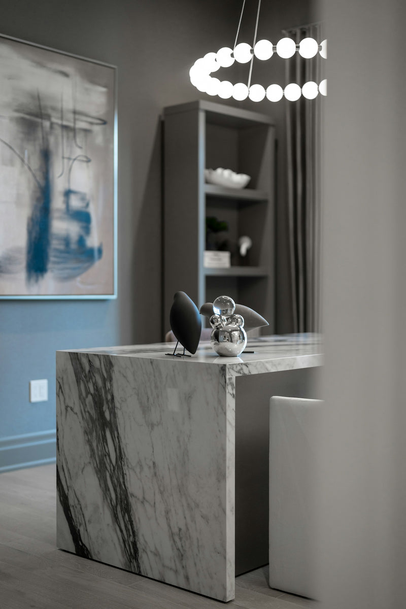 Contemporary office interior with a sleek marble desk and chandelier.
